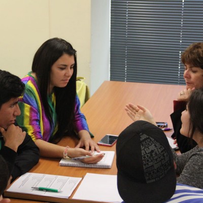 Cuatro estudiantes trabajan junto a docente.