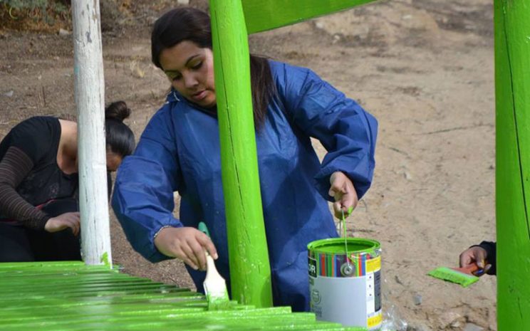 Una estudiante pinta de color verde uno de los juegos de la escuela.