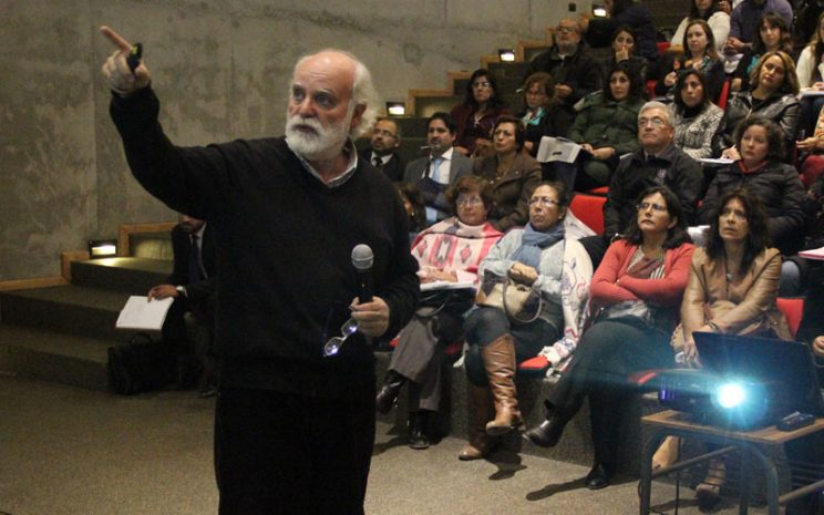 Sergio Canals en primer plano, explica y apunta a su presentación en pantalla mientras lo observa la audiencia.