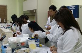 Estudiantes observan equipamiento en mesón de laboratorio.
