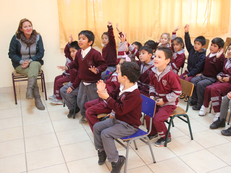 Los niños y niñas participan levantando la mano en sus asientos.