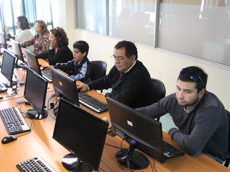Colaboradores e hijos trabajan en computadores durante la hora del código.