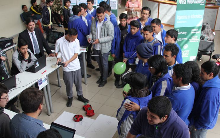 Estudiante maneja un robot a control remoto en el stand del Área de Informática.