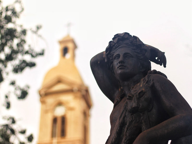 En primer plano, estatua. Al fondo, catedral de La Serena.