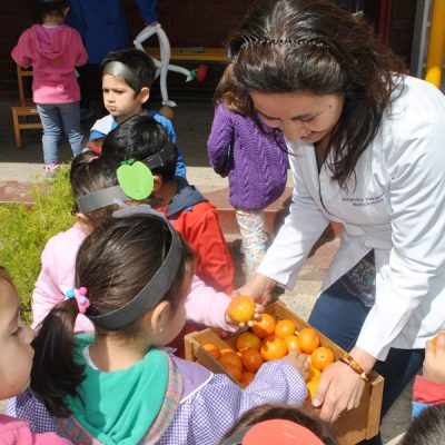 Alumnos recibiendo naranjas