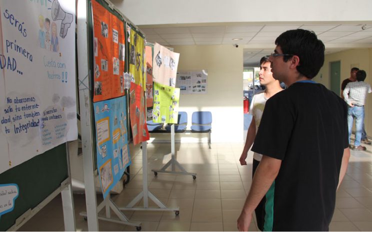 Dos estudiantes observan algunos afiches de la exposición.