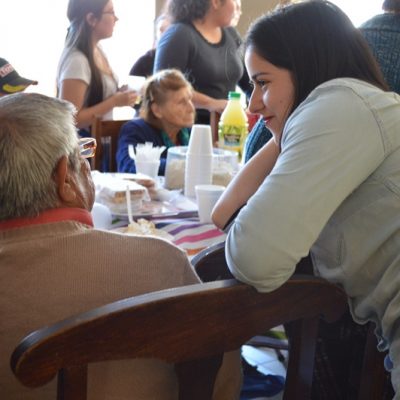 Una estudiante escucha atenta a un abuelito del condominio de adultos mayores Villa La Primavera, de La Pintana.