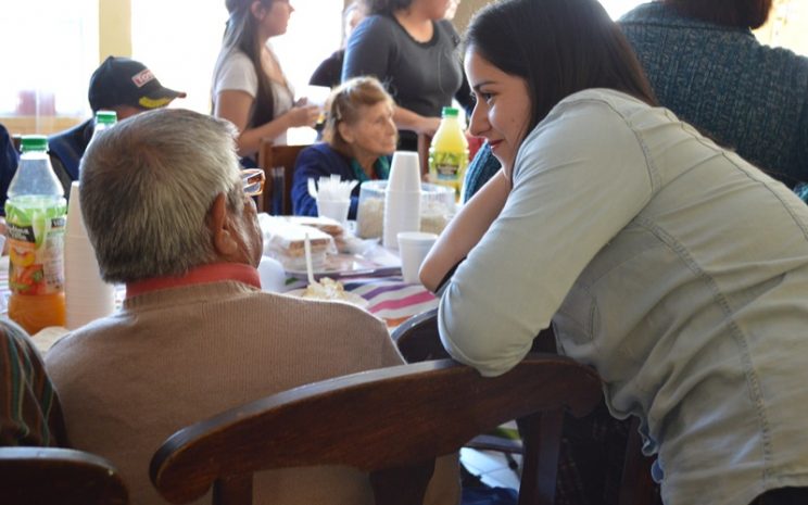 Una estudiante escucha atenta a un abuelito del condominio de adultos mayores Villa La Primavera, de La Pintana.