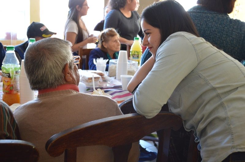 Una estudiante escucha atenta a un abuelito del condominio de adultos mayores Villa La Primavera, de La Pintana.