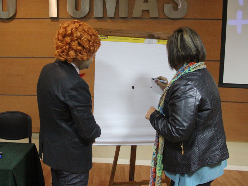 Profesora participante dibuja en un papel junto al conferencista.