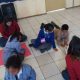 Niños dibujan en el suelo, mientras observan dos alumnos de Psicología.