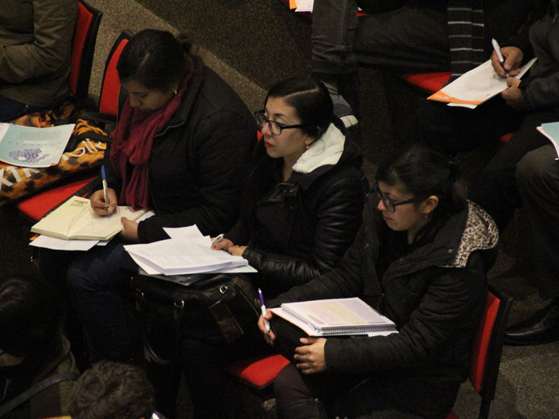 Grupo de tres participantes, tomando nota y observando la charla.