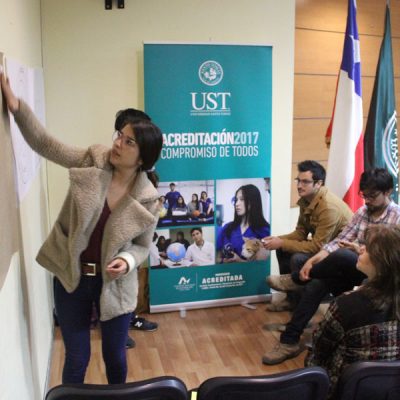 Monitora del taller pega elemento en papelógrafo durante la actividad.