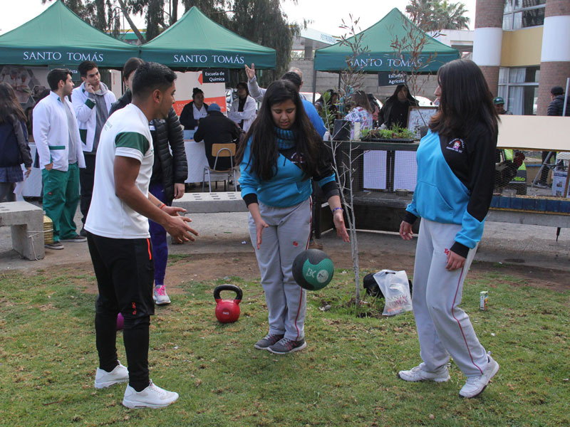 Estudiante de Preparador Físico enseña ejercicios con balón a dos alumnas.
