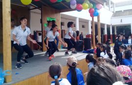 Alumnas bailando zumba en escenario motivando a estudiantes del colegio.