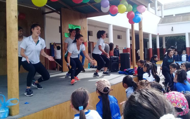 Alumnas bailando zumba en escenario motivando a estudiantes del colegio.