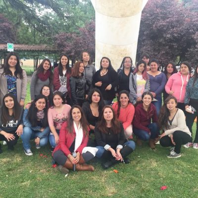 Alumnas del área de educación agrupados en la cancha de pasto, bajo un toldo blanco.