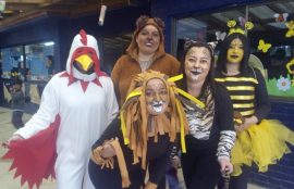 Cinco estudiantes disfrazadas de gallo, león, oso, tigre y abeja, posan sonriendo frente la cámara.