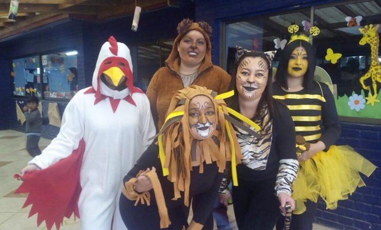 Cinco estudiantes disfrazadas de gallo, león, oso, tigre y abeja, posan sonriendo frente la cámara.