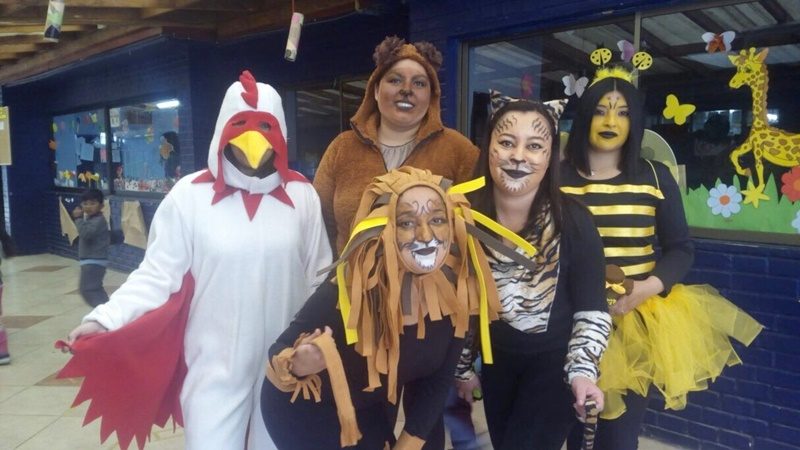 Cinco estudiantes disfrazadas de gallo, león, oso, tigre y abeja, posan sonriendo frente la cámara.