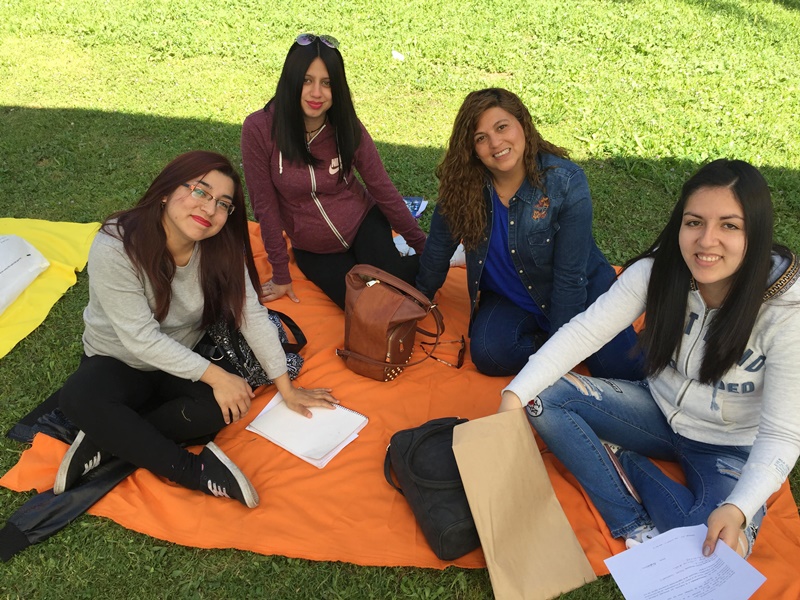 Cuatro alumnas están sentadas sobre una manta de color anaranjado, en el pasto, mientras realizan actividades de autoevaluación.