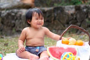 Bebé junto a canasto con frutas. 